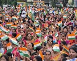 Large group of women at a patriotic ra;;y, actively waving small flags and holding hands
